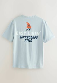 Vaaleansininen puuvillapaita, jossa on hymyilevä oranssi evä-animaatio ja teksti "EASY LIVIN’ SURFBOARDS and FINS" tummansinisellä ja valkoisella.
