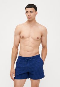 Marineblå badshorts med en struktureret ribbet mønster, elastisk talje og snørelukning. Casual design, der er velegnet til strandbrug.