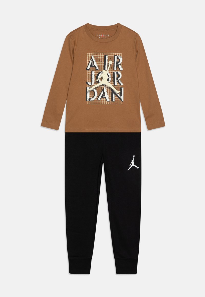 Maglietta a maniche lunghe marrone con grafica "AIR JORDAN" e pantaloni della tuta neri con un logo bianco sulla gamba sinistra. Tessuto morbido in misto cotone.