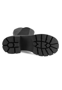 Zwarte waterdichte laars met een rubberen zool. De zool heeft diepe profielen voor grip. De bovenkant toont een combinatie van gladde en gestructureerde materialen.