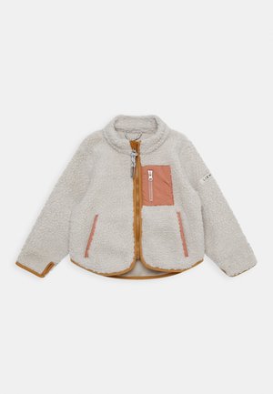Veste en polaire crème avec bordure beige, fermeture éclair frontale, poche poitrine zippée rose et poches latérales sur fond blanc.