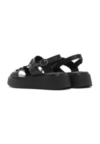 Sandali platform neri in pelle, con punta aperta, dettaglio con fibbia e cinturino regolabile. Suola spessa con finitura texturizzata. Forma arrotondata.