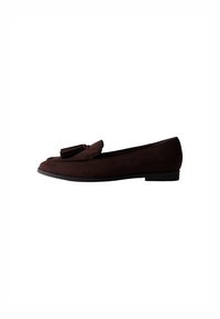 Mocasín de ante marrón con punta redondeada y borlas decorativas en la parte superior. Suela plana con un diseño minimalista y textura suave.