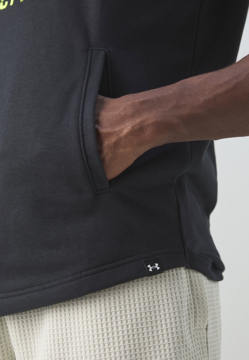 Svart kortärmad skjorta med en känguruficka och en logotagg, ihop med ljusa texturerade shorts. Mjuk tygfinish.