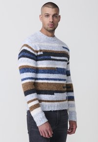 Multicolor gebreide trui met horizontale strepen in blauw, zwart, bruin en wit. Ronde halslijn en geribde boorden bij de mouwen.