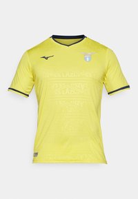 Dzeltena īsām piedurknēm futbolbikses krekls ar V veida kakla izgriezumu, ar smalku rakstu un tumši ziliem akcentiem. SS Lazio logo kreisajā krūtī.