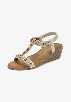 Beige Keilsandale mit gepolstertem Fußbett, goldener Kette und Perlendekorationen an den Riemen sowie elastischem Rückriemen für sicheren Sitz.