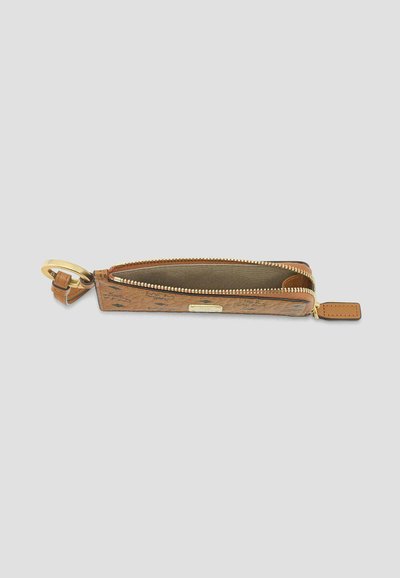 Pochette à clés en cuir marron avec fermeture éclair dorée partiellement ouverte et anneau porte-clés rond doré attaché sur fond neutre.