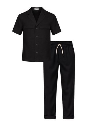 Camicia nera a maniche corte con bottoni e tasche con patta abbinata a pantaloni neri con coulisse e orli risvoltati.