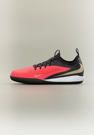 Κόκκινο και μαύρο αθλητικό παπούτσι Nike με χρυσό λογότυπο swoosh, μαύρα κορδόνια, λευκή μεσαία σόλα και μαύρη σόλα, τοποθετημένο σε απλό φόντο.