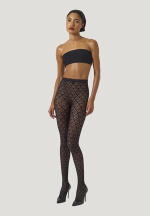 Calze nere a fantasia con un design a ragnatela, indossate con un top bandeau nero e tacchi alti, che mettono in evidenza dettagli intricati e texture.