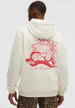 Man draagt witte hoodie met rode afbeelding van hardloopschoenen, wolken, sterren en de tekst "voor alle lopers" op de achterkant.