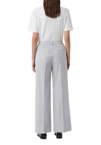 Lichtgrijze wijde broek met een gestructureerd oppervlak, twee achterzakken en een gladde tailleband, gecombineerd met een eenvoudig wit t-shirt.