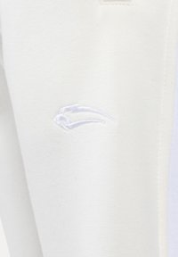 Weiße Jogginghosen aus weichem Material, mit einem dezenten, weißen Sticklogo, minimalistischem Design und elastischem Bund.