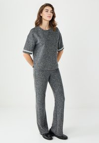 Ensemble à deux pièces en tricot gris avec des manches courtes et une bordure décorative, composé d'un haut à coupe décontractée et d'un pantalon droit, agrémenté de chaussures noires.