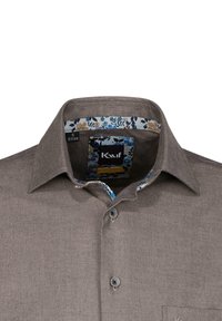 Camicia marrone a bottoni con finitura testurizzata, colletto interno a fantasia floreale e tasca sul lato sinistro. L'etichetta mostra la taglia S (37/38).