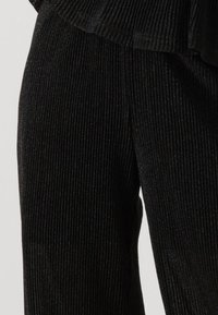 Zwarte ribstof broek met een subtiele glans, voorzien van een wijde pijpenontwerp en verticale strepen voor textuur.