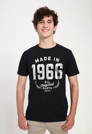 Sort bomulds T-shirt med hvid tekst: "MADE IN 1966" og "ALL Original PARTS" med dekorative laurbær accenter. Korte ærmer, rund halsudskæring.