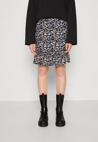 Gonna mini con motivo floreale in nero, blu e crema; presenta un orlo arricciato. Abbinata a stivali alti in pelle nera.