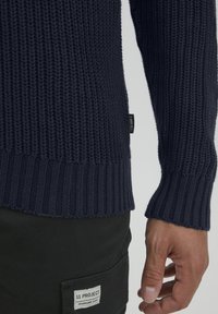 Maglione lavorato a maglia blu navy con un motivo testurizzato, polsini e orlo a costine, con un piccolo etichetta del marchio di lato.