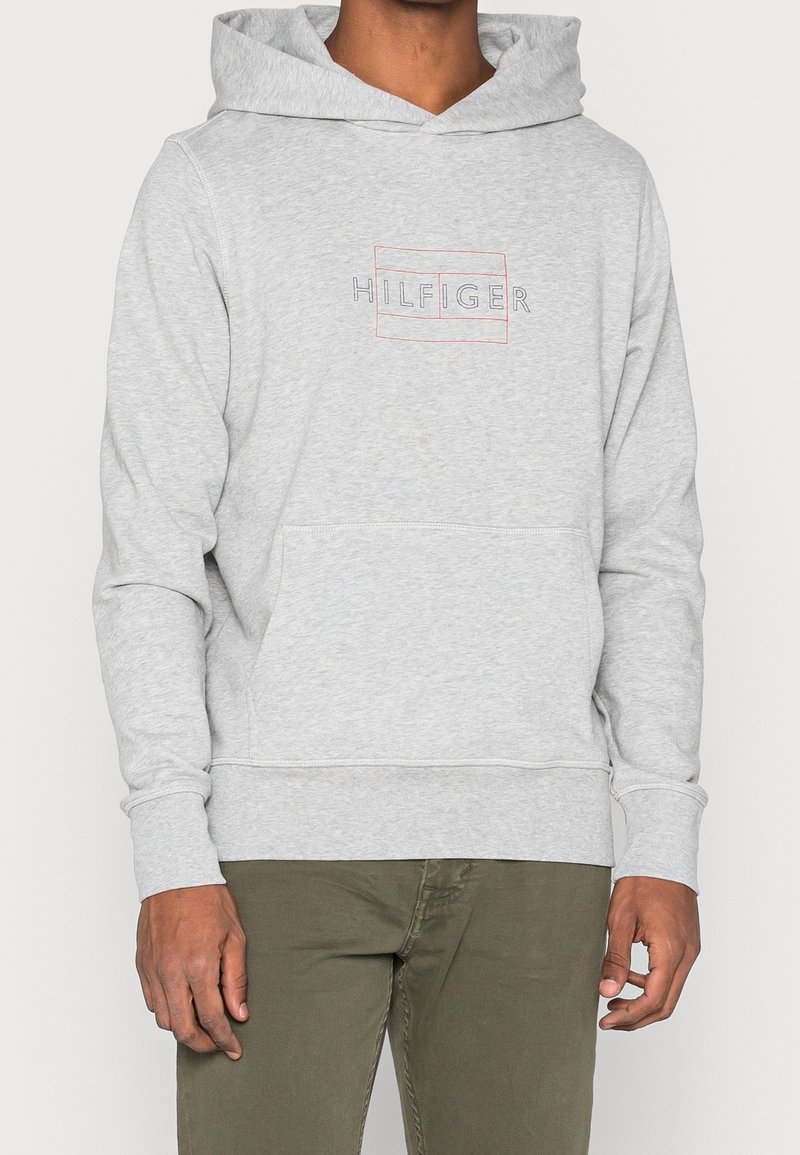 Felpa grigia chiara realizzata in tessuto morbido, con tasca frontale, polsini a coste e un logo "HILFIGER" multicolore sul petto.
