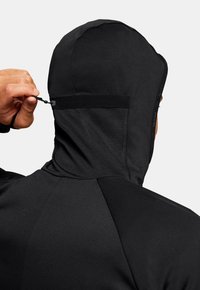 Schwarzer technischer Hoodie mit einer strukturierten Kapuze, die über einen Sicherungsriemen verfügt, glatter Textur und flachen Nähten für zusätzlichen Komfort.