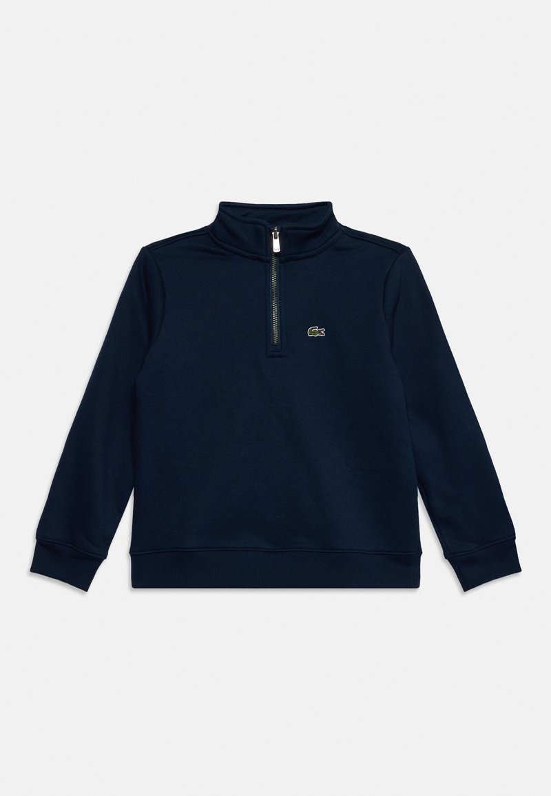 Pull bleu marine à manches longues avec demi-fermeture éclair et petit logo crocodile sur la poitrine, poignets et ourlet côtelés, posé à plat sur fond blanc.