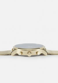 Montre-bracelet dorée avec un cadran sombre, trois boutons sur le côté et un bracelet en maille texturée, présentant une finition métallique brillante.