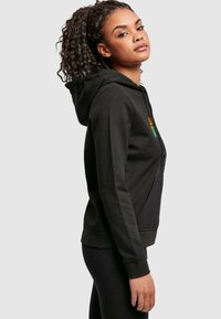 Sort hoodie med frontlomme, snøre i hætten og farverig tekstgrafik. Blødt, glat stof med en tætsiddende design og ribbede manchetter.