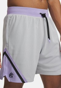 Grå nätträningsshorts med lavendelfärgad midja, med en svart rand och lila detaljer, inklusive logotypdetalj på sidan.