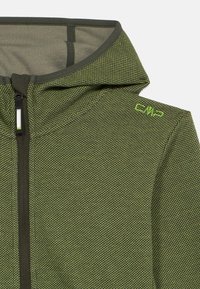 Πράσινη φούτερ με φερμουάρ που διαθέτει καλοσχηματισμένη κουκούλα, υφή υφάσματος και διακριτό γεωμετρικό μοτίβο. Λογότυπο σε φωτεινό πράσινο χρώμα στον ώμο.