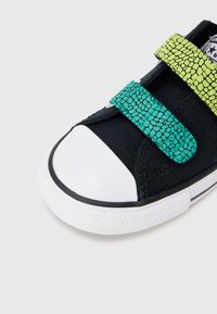 Μαύρο καμβά αθλητικό παπούτσι με λευκή λαστιχένια μύτη και σόλα. Διαθέτει δύο υφασμάτινες λουρίδες βέλκρο με υφή σε πράσινο και μοτίβο ακουαμαρίνας φιδιού.