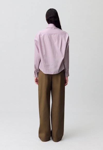 Camisa de cuadro rojo y blanco de botones con un dobladillo redondeado, combinada con pantalones marrones de pierna ancha y cintura alta. Diseño sencillo, tejido ligero.