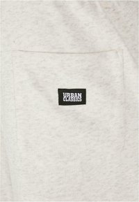 Gray, textured fabric with a single chest pocket; features a black "URBAN CLASSICS" label on the pocket. Simple design, casual style.