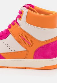 Vysoké tenisky s kombinací růžové, oranžové a bílé kůže, s perforovanými detaily, brandingem Coach a texturovanou akcentní vrstvou.