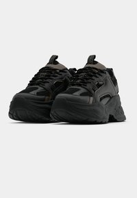 Černé sportovní boty s kombinací texturované síťoviny a syntetických materiálů, vybavené masivní podrážkou a kontrastními šedými detaily.