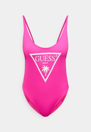 Lyserød badedragt i ét stykke lavet af glat stof. Har et hvidt trekantsdesign med "GUESS BEACH" og en palmegrafik. Tynde stropper.