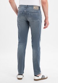 Svetlomodré džínsové nohavice so slim fit strihom, s logom na zadnej strane, dvoma zadnými vreckami a hladkým tkaným povrchom.