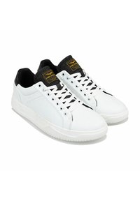 Witte leren sneakers met een zwarte tong en veters, voorzien van een gelaagd zwart detail op de hiel en een gele merklabel op de tong.