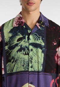 Korte mouw shirt met een mix van grafische prints in groen, paars en zwart, met knopen en een borstzak. Glad textuur van de stof.