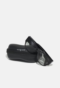 Ochelari de soare negri cu ramă pătrată, având lentile gri fumurii, așezați pe un toc negru cu fermoar, cu cuvântul "vogue" imprimat în alb.