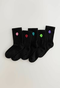 Sorte sokker med ribbet tekstur, der har farverige smiley ansigtsdesigns i pink, rød, grøn, blå og lilla på den øverste del.