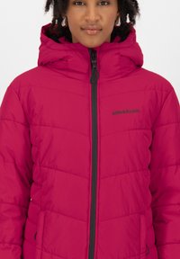 Puffjacke in leuchtendem Pink mit einem gesteppten Design, Kapuze und einem Frontreißverschluss mit kontrastierender schwarzer Akzentuierung. Branding auf der Brust.