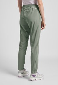 Lichtgroene, lichtgewicht broeken met een elastische tailleband. Kenmerken zijn een taps toelopend ontwerp en een subtiele logo aan de achterkant, gecombineerd met sneakers.