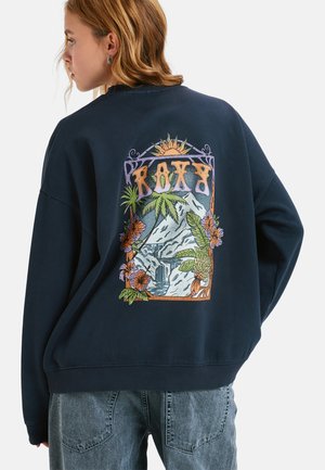 Granatowy sweatshirt z kolorową grafiką na plecach, przedstawiającą palmy, kwiaty, wodospad oraz słowo "ROXY" w ozdobnej czcionce.