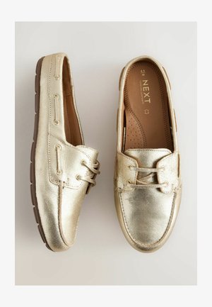 Kultaiset nahka loaferit, joissa on sileä pinta, koristeellinen nauhoitus ja pehmustettu pohja. Varustettu kestävällä kumipohjalla pidon varmistamiseksi.