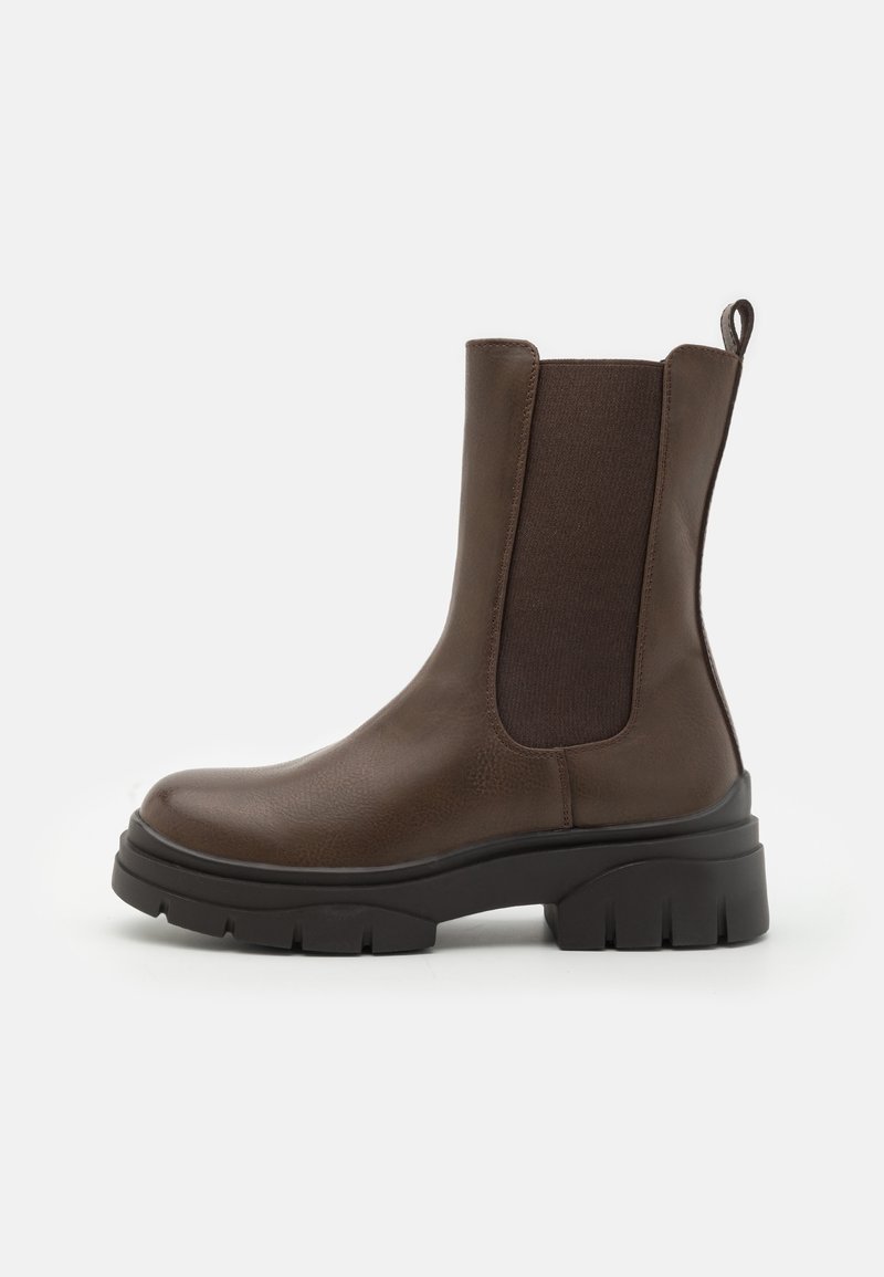 Botte mi-mollet en cuir marron avec panneau latéral élastique, languette de tirage et semelle crantée noire épaisse, vue de profil sur fond blanc.