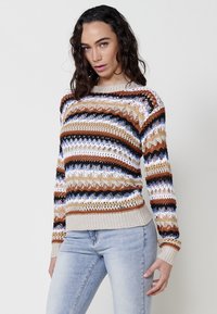 Multicolored knit sweater featuring horizontal stripes in beige, brown, navy, and white. Textured, open-weave design with ribbed cuffs.