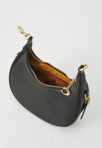 Sac à main en cuir noir avec une forme incurvée, quincaillerie dorée et fermeture éclair. L'intérieur présente une doublure marron avec une poche.