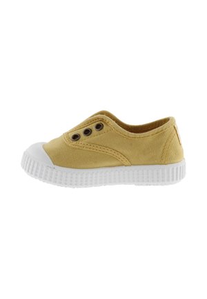 Scarpa slip-on gialla in canvas con punta in gomma bianca e suola texture, dotata di due occhielli su ciascun lato per la ventilazione.